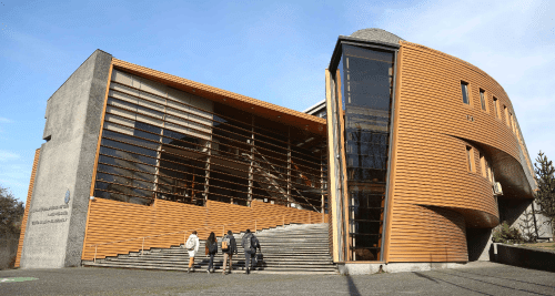 Fachada del Campus Villarrica de la Pontificia Universidad Católica de Chile. Se ven estudiantes ingresando al edificio Monseñor Paul Wevering.